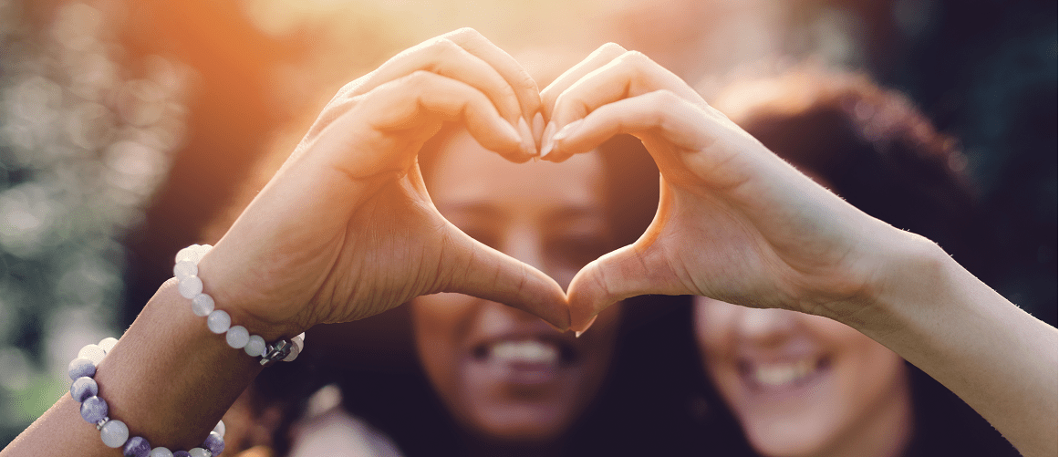 Smiling women creating a heart with their hands