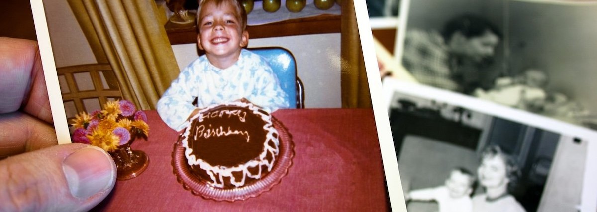 Hand holds Vintage photograph of child and birthday cake - stock photo