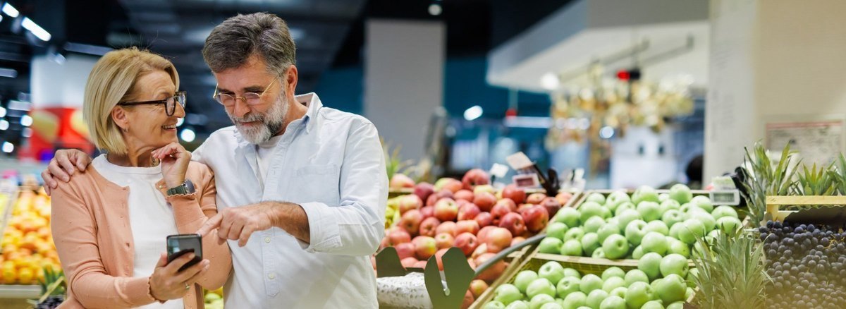 Coppia senior al supermercato con cellulare