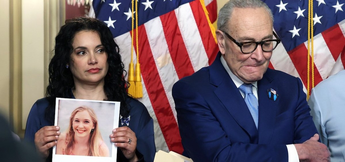 WASHINGTON, DC - FEBRUARY 10: Sharlene Rochard (L), Jeffrey Epstein victim, holds a photograph of Virginia Giuffre, as she stands next to U.S. Senate Minority Leader Chuck Schumer (D-NY) during a news conference at the U.S. Capitol on February 10, 2026 in Washington, DC. Schumer introduced "Virginia's Law," legislation to eliminate the statute of limitations that Schumer argues has shielded traffickers and denied survivors their day in court. (Photo by Kevin Dietsch/Getty Images)