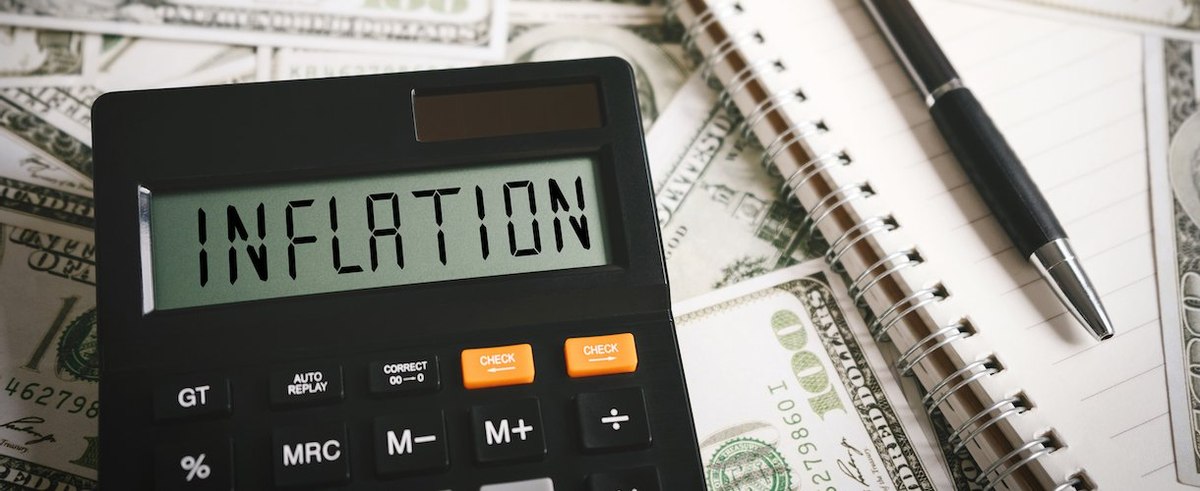 The word inflation on a calculator with U.S. dollars in the background
