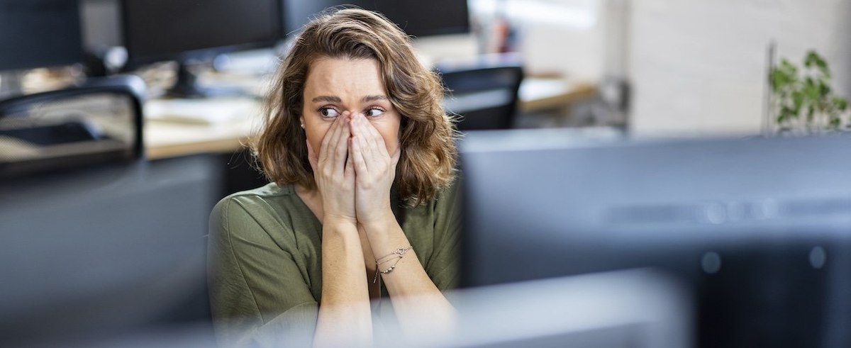 Worried businesswoman covering face sitting in office