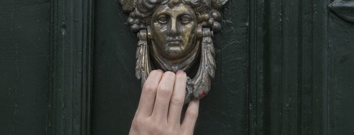 Woman's hand on door knocker, close-up - stock photo