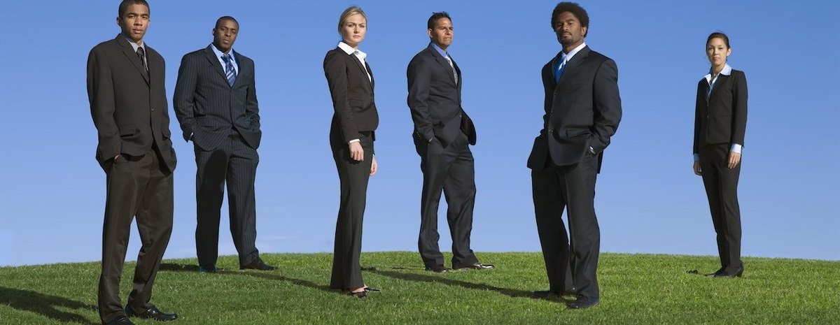 Business people standing outdoors in grass - stock photo